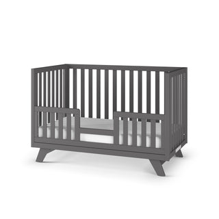 The Child Craft Toddler Guard Rail in Cool Gray features open slatted sides and a partial guardrail on one side, standing on angled legs against a white background.