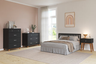 Modern bedroom with a bed, Child Craft Soho 3-Drawer Dresser in Ebony, black nightstand, soft beige bedding, large window with sheer curtains, rainbow artwork, and neutral decor on a light wood floor.