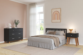 Modern bedroom featuring a neatly made bed with a black headboard, Child Craft Soho 3-Drawer Dresser in Ebony, matching nightstand, beige walls, large window with sheer curtains, framed rainbow art above the bed, and stylish lamp and decor.