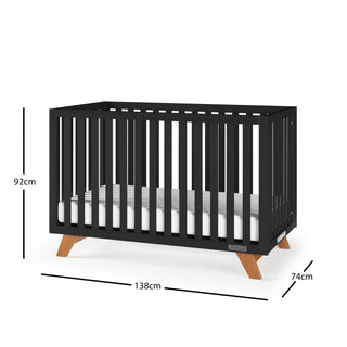 The Child Craft Soho 4-in-1 Convertible Crib in Ebony features vertical slats, angled wooden legs, a white mattress, and measures 92cm H x 138cm L x 74cm W. Easily converts into a toddler bed as your child grows.