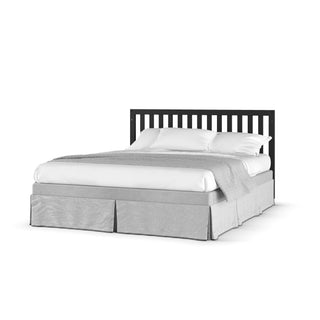 A neatly arranged Soho 4-in-1 Convertible Crib by Child Craft in Ebony features white pillows and sheets, a light gray blanket, gray bed skirt, and black slatted headboard against a plain white background.