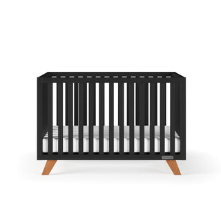 The Child Craft Soho 4-in-1 Convertible Crib in Ebony features a mid-century modern design, includes a white mattress, and easily converts into a toddler bed.