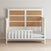 The Child Craft Toddler Guard Rail in White/Brown features a high headboard with light brown panels, low side rails, and gray mattress, set on a light wood floor against a plain wall—perfect for crib conversion.