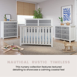 A nursery featuring white and gray furniture, including the Child Craft Ocean Grove Double Dresser, a crib, two dressers, and a wooden rocking horse, decorated with plants and toys. Nautical Farmhouse Timeless. Calming coastal feel.