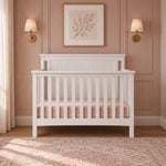Matte white Child Craft Scout 4-in-1 Convertible Crib with slatted sides and a beadboard headboard in a nursery.