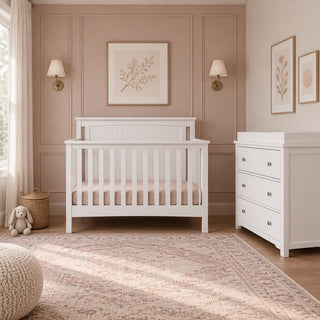 Matte white Scout 4-in-1 Convertible Crib next to a matching three-drawer changing table in a nursery.