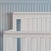 Close-up of the Child Craft Scout 4-in-1 Convertible Crib in Matte White with vertical slats, set against a light blue paneled wall for a calm, minimalistic nursery vibe.