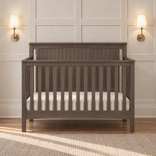 Child Craft Scout 4-in-1 Convertible Crib in Dapper Gray, featuring a wooden frame with vertical slats and a beadboard headboard.