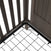Close-up of the Child Craft Scout 4-in-1 Convertible Crib in Dapper Gray, showing its sturdy metal bed frame with a black grid base attached to wooden panels with vertical slats and a beadboard headboard.