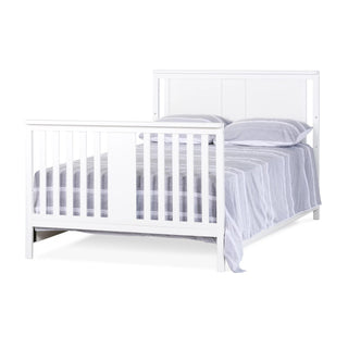 The Child Craft F06401 full-size bed rails in matte white feature vertical slats on the headboard and footboard, crafted from durable pine wood, shown with a light gray striped blanket and matching pillows.