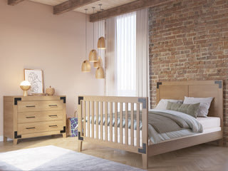 A cozy bedroom features a wooden bed and dresser, exposed brick, pendant lights, and sheer-curtained windows. Warm neutral tones enhance comfort, while Child Craft’s F06464 Full-Size Bed Rail - Nutmeg adds safety and versatility for families.