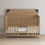 The Child Craft F09514 Toddler Guard Rail in Nutmeg features side guard rails, a high headboard, and low footboard. Set against a light wall on hardwood flooring, it's the perfect stylish crib conversion for your growing child.