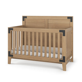 The Child Craft Lucas 4-in-1 Convertible Crib in Nutmeg features vertical slats, a high back panel, black metal corner accents, and a white mattress. The crib is empty and set against a white background.
