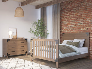 A bedroom featuring the Child Craft Lucas 4-in-1 Convertible Crib in Dusty Heather and a brick wall.
