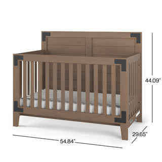 The Child Craft Lucas 4-in-1 Convertible Crib in Dusty Heather features slatted wooden sides, black metal corner accents, and a visible mattress. Dimensions: 54.84" W x 29.65" D x 44.09" H.