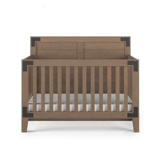 The Child Craft Lucas 4-in-1 Convertible Crib in Dusty Heather features vertical wooden slats, black metal corner accents, and is shown from the front with a white mattress on a white background.