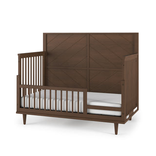 The Child Craft Surrey Hill 4-in-1 Convertible Crib in Toasted Chestnut features a tall paneled headboard, slatted sides, and includes a white mattress, shown against a white background.