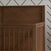 A close-up of the Child Craft Surrey Hill 4-in-1 Convertible Crib in Toasted Chestnut, featuring vertical slats and a diagonal panel design, stands against a white wall with a black, diagonal-line pattern.