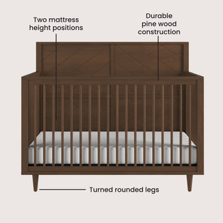 Front view of the Child Craft Surrey Hill 4-in-1 Convertible Crib in Toasted Chestnut, featuring slatted sides, turned rounded legs, a geometric-patterned back panel, two mattress height positions, and durable pine wood construction.
