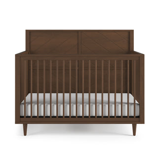 The Child Craft Surrey Hill 4-in-1 Convertible Crib in Toasted Chestnut features dark brown wood, vertical slats, angled legs, a solid geometric headboard, and includes a white mattress.