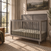 Lunar Gray Child Craft Surrey Hill 4-in-1 Convertible Crib with a paneled headboard featuring an X-shaped design.