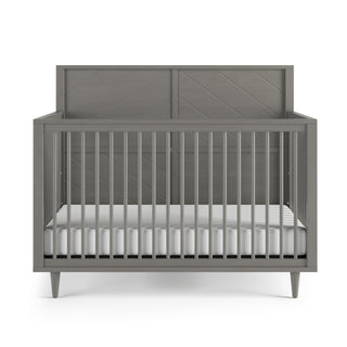 The Child Craft Surrey Hill 4-in-1 Convertible Crib in Lunar Gray features a modern, minimalist design with vertical slats, a solid headboard, and a white mattress, shown on a white background.