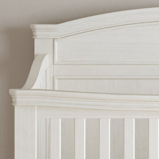 Close-up of the Child Craft Westgate 4-in-1 Convertible Crib in Vintage Linen, featuring decorative molding, paneled design, and adjustable mattress support against a light beige wall.