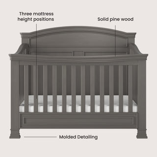 The Child Craft Westgate 4-in-1 Convertible Crib in Chelsea Grey features an arched headboard, slatted sides, elegant base molding, solid pine wood construction, and three adjustable mattress positions.