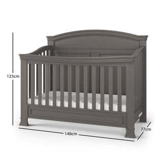 The Child Craft Westgate 4-in-1 Convertible Crib in Chelsea Grey features slatted sides, an arched headboard, and pine wood construction. It measures 123 cm high, 148 cm wide, 77 cm deep, and includes an adjustable design with a white mattress.