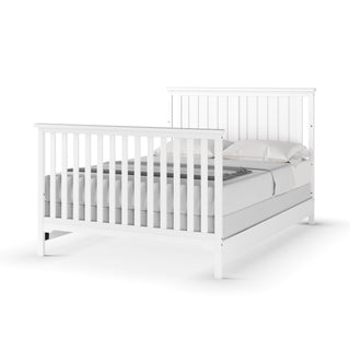 The Child Craft F06401 Full-Size Bed Rails in matte white feature sturdy pine wood construction and a simple modern design, shown here with a bed frame, mattress, gray bedding, and two pillows for lasting support and style.