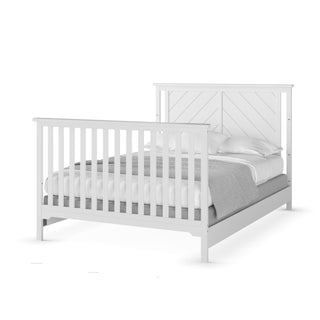 A matte white wooden bed frame by Child Craft with vertical slats on the headboard and footboard, sturdy F06401 full-size pine rails, dressed in white pillows, sheets, and a gray blanket.