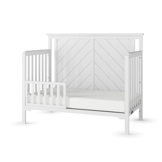 The Child Craft Hampton Flat Top 4-in-1 Convertible Crib in Matte White features sturdy pine wood, a chevron-patterned headboard, slatted sides, partial safety rail, and non-toxic finishes, shown against a plain white background.