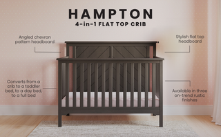 The Child Craft Hampton Flat Top 4-in-1 Convertible Crib in Dapper Gray features a flat top headboard with a chevron pattern. Set against a pink dotted wall, it converts to multiple bed types and comes in rustic finishes.