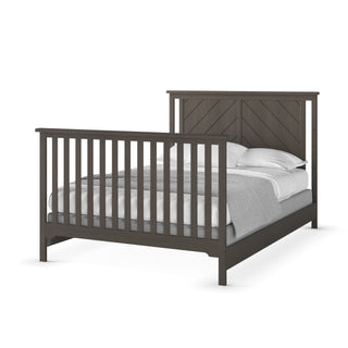The Child Craft F06401 Full-Size Bed Rails in Matte White provide sturdy support for a bed with vertical slats on the footboard and a chevron headboard, shown with white pillows and gray bedding.