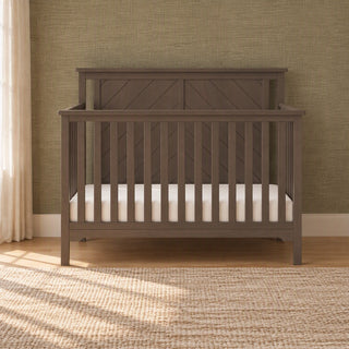 Hampton Flat Top 4-in-1 Convertible Crib in Dapper Gray, made of pine wood with a flat top and diagonal slat detailing on the headboard.