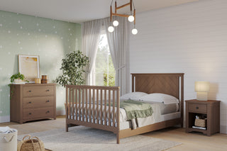 Cozy bedroom with a wooden bed, dresser, and the Harmony Nightstand in Dusty Heather by Child Craft for bedside storage. Green accent wall with white stars, white shiplap wall, large curtained window, potted plant, modern ceiling light, and child-safe finishes.