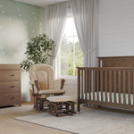 A cozy nursery featuring the Child Craft Hampton Flat Top 4-in-1 Convertible Crib in Dusty Heather, matching dresser, beige rocker with ottoman, star-patterned green wall, potted plant, large window with white curtains, and a light gray rug on wood floor.