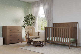 A cozy nursery featuring the Child Craft Hampton Flat Top 4-in-1 Convertible Crib in Dusty Heather, matching dresser, beige rocker with ottoman, star-patterned green wall, potted plant, large window with white curtains, and a light gray rug on wood floor.