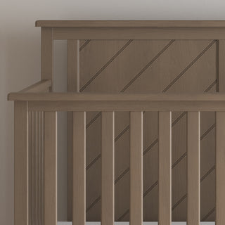 Close-up of the Child Craft Hampton Flat Top 4-in-1 Convertible Crib in Dusty Heather, featuring vertical slats and a diagonally paneled headboard. Its smooth finish and versatile design offer long-lasting functionality.