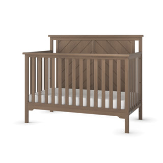 The Child Craft Hampton Flat Top 4-in-1 Convertible Crib in Dusty Heather features sturdy pine wood, vertical slats, a solid headboard, adjustable mattress support, a natural brown finish, and is shown with a white mattress.