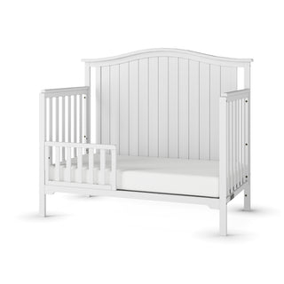 The Child Craft F09501 Toddler Guard Rail in Matte White features sturdy wood construction, an arched headboard, open sides, and a guard rail on one side, displayed against a plain white background.