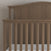 A close-up of the Child Craft Hampton Arch Top 4-in-1 Convertible Crib in Dusty Heather, featuring a high curved headboard, vertical slats, simple design, and a white mattress.