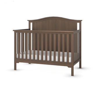 The Child Craft Hampton Arch Top 4-in-1 Convertible Crib in Dusty Heather features vertical slats, a gently curved headboard, and a classic wooden design. The crib includes only a white mattress and is shown empty.
