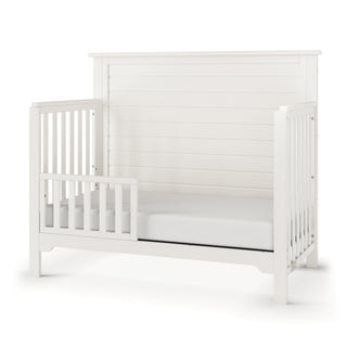 The Child Craft F09501 Toddler Guard Rail in Brushed Cotton offers a modern, minimalist design with sturdy slats and open sides for easy access, echoing the clean style of Child Craft cribs and allowing simple crib-to-toddler bed conversion.