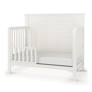 The Child Craft F09501 Toddler Guard Rail in Brushed Cotton offers a modern, minimalist design with sturdy slats and open sides for easy access, echoing the clean style of Child Craft cribs and allowing simple crib-to-toddler bed conversion.