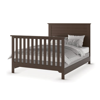 The Child Craft F06401 Full-Size Bed Rails in Brushed Truffle support a dark brown wooden bed frame with vertical slats on the headboard and footboard, neatly made with white and gray bedding and pillows.