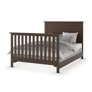 The Child Craft F06401 Full-Size Bed Rails in Brushed Truffle support a dark brown wooden bed frame with vertical slats on the headboard and footboard, neatly made with white and gray bedding and pillows.
