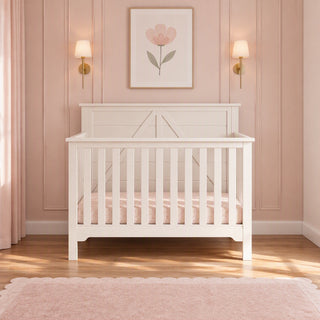 Child Craft Woodland 4-in-1 Convertible Crib in Brushed Cotton with an arched backboard and a patterned mattress in a room with pink paneled walls.