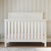 Child Craft Woodland 4-in-1 Convertible Crib in Brushed Cotton, featuring a white pine slatted design with a pale pink mattress and adjustable mattress support.