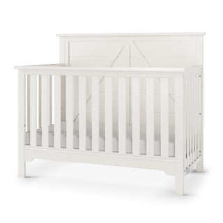 The Child Craft Woodland 4-in-1 Convertible Crib in Brushed Cotton features slatted sides, a solid panel headboard, and a modern farmhouse design. Shown empty against a plain white background.